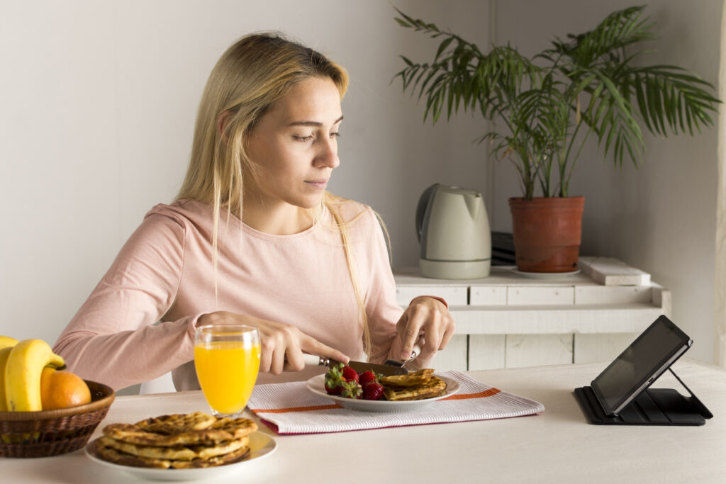 A girl enjoying waffles while using a tablet, juxtaposed with intermittent fasting